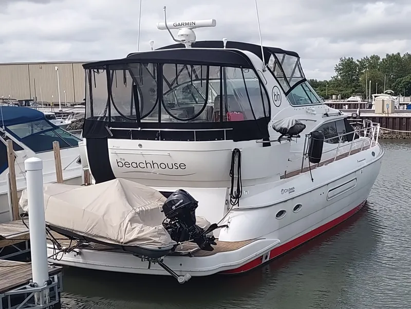 The Image of 2001 Cruisers Yachts 4450 Express Motoryacht docked at marina, covered dinghy attached. - 0