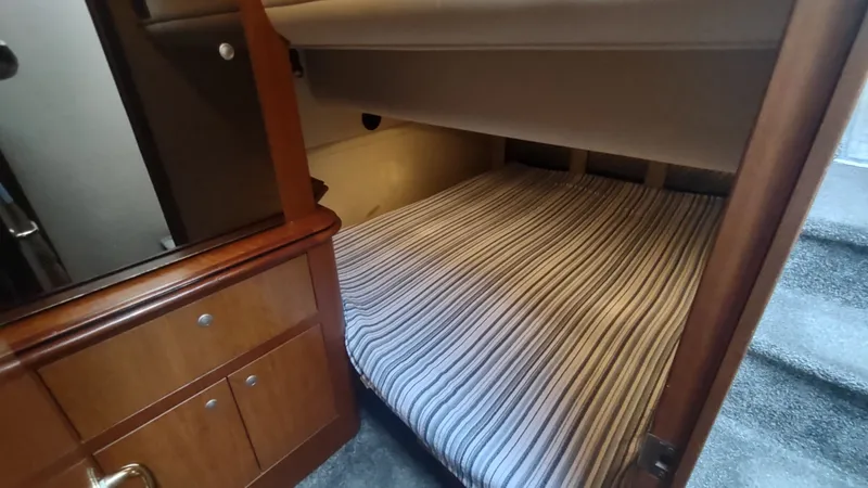 Slide: The Image of 2001 Cruisers Yachts 4450 Express Motoryacht cabin with striped bedding and wooden cabinetry. - 39