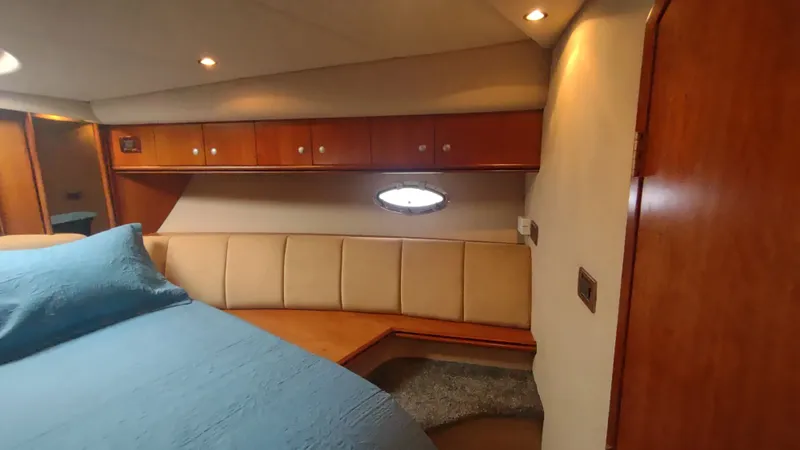 Slide: The Image of 2001 Cruisers Yachts 4450 Express Motoryacht interior cabin with wood paneling and blue bedding. - 44
