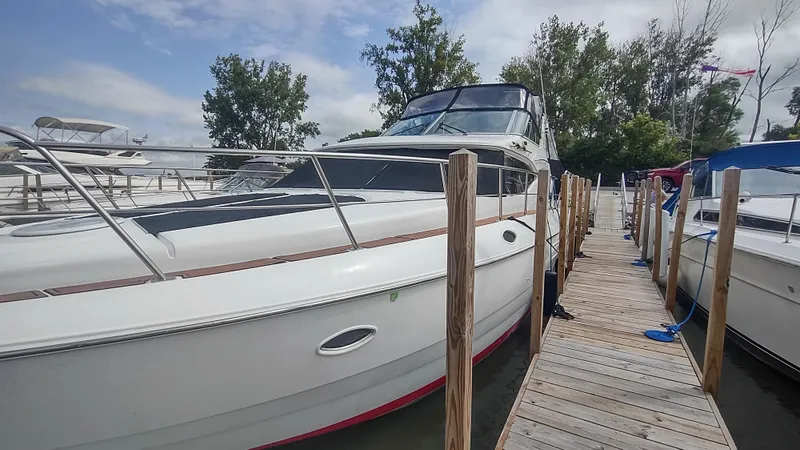 Slide: The Image of 2001 Cruisers Yachts 4450 Express Motoryacht docked at marina, surrounded by trees and boats. - 6