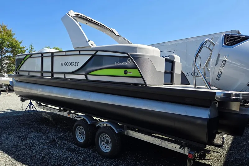 Slide: The Image of 2025 Godfrey Monaco 255 SB pontoon boat on trailer, featuring sleek design and Honda engine. - 2