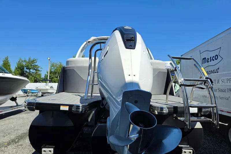 Slide: The Image of 2025 Godfrey Monaco 255 SB pontoon boat with outboard motor and ladder, parked outdoors. - 4