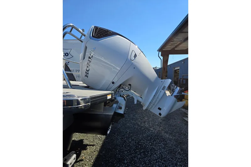 Slide: The Image of 2025 Godfrey Monaco 255 SB with Honda outboard motor, parked outdoors. - 43