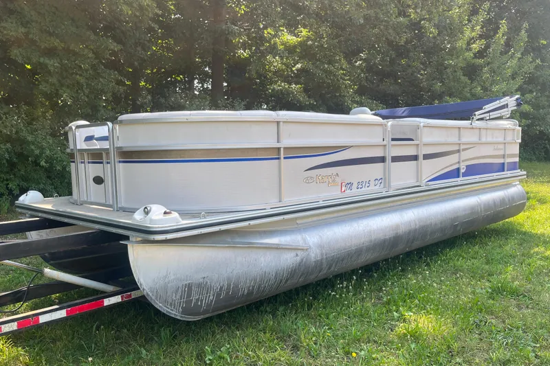 The Image of 2007 Harris-Kayot Super Sunliner 220 O/B pontoon boat on trailer, parked on grass. - 1