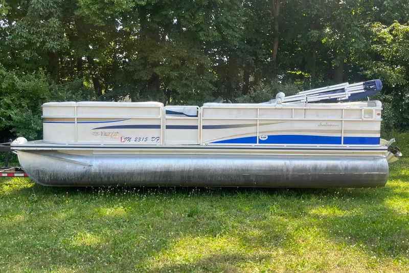 Slide: The Image of 2007 Harris-Kayot Super Sunliner 220 O/B pontoon boat on grass, surrounded by trees. - 2