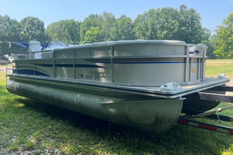 Slide: The Image of 2007 Harris-Kayot Super Sunliner 220 O/B pontoon boat on trailer, surrounded by trees. - 7