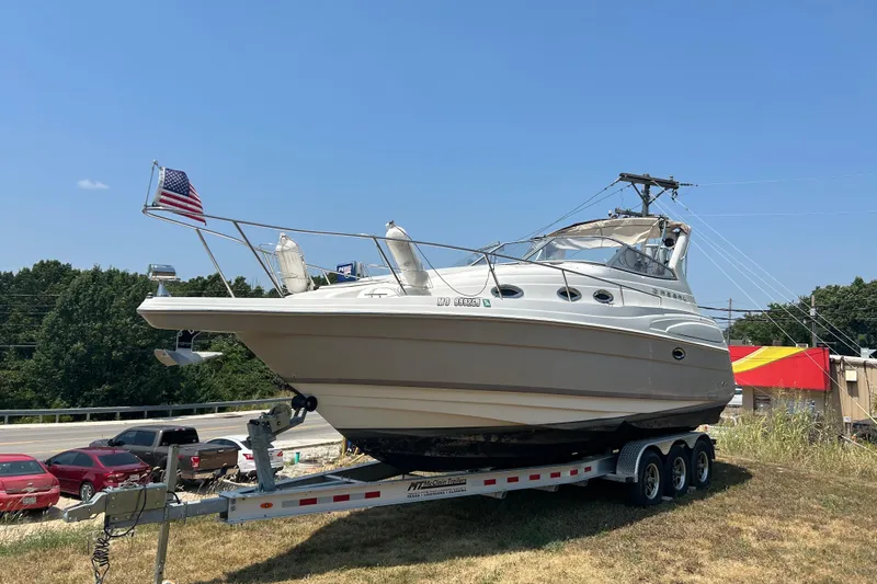 The Image of 2003 Regal Commodore 2860 boat on trailer, American flag, parked near road. - 0
