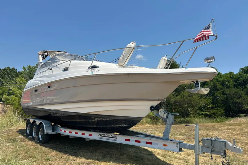 Slide: The Image of 2003 Regal Commodore 2860 boat on trailer with American flag, parked on grass. - 2
