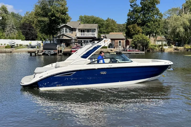 Slide: The Image of 2026 Sea Ray SDX 270 boat on calm water near houses. - 32