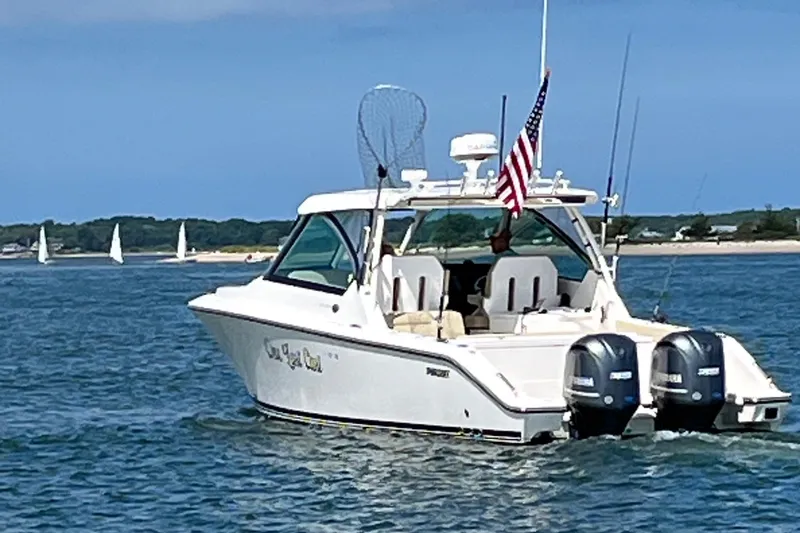 The Image of 2016 Pursuit DC 325 Dual Console boat cruising on a sunny day with sailboats in the background. - 0