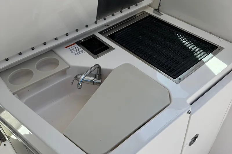 Slide: The Image of 2016 Pursuit DC 325 Dual Console boat kitchenette with sink, faucet, and grill. - 15