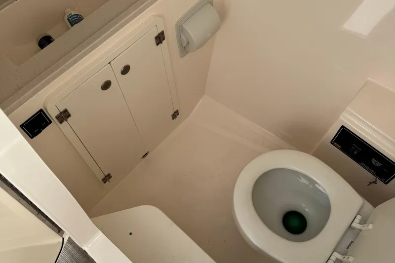 Slide: The Image of 2016 Pursuit DC 325 Dual Console boat bathroom with toilet and storage cabinet. - 19