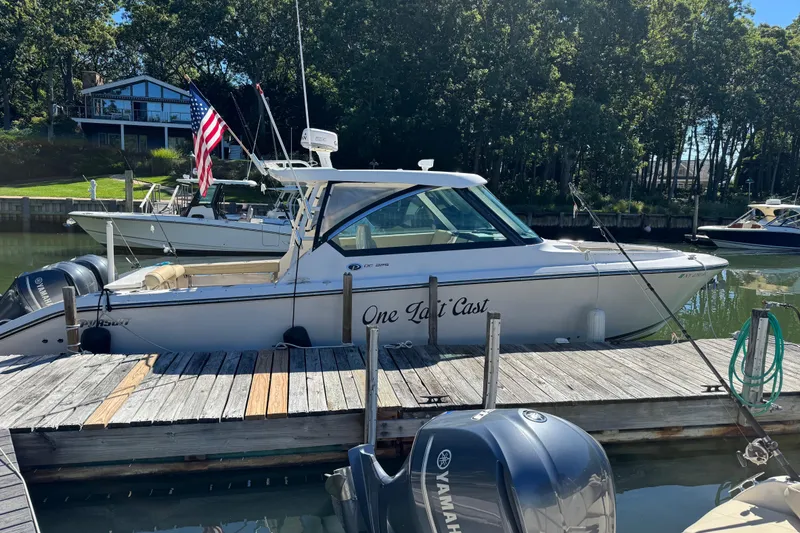 Slide: The Image of 2016 Pursuit DC 325 Dual Console boat docked, featuring Yamaha engines and American flag. - 6