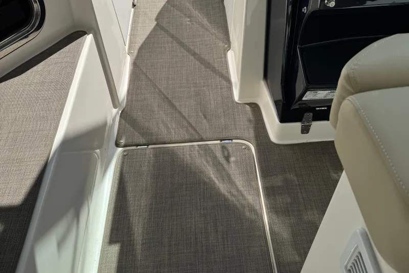 Slide: The Image of 2016 Pursuit DC 325 Dual Console interior with gray carpet and beige seating. - 9