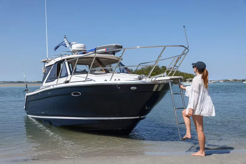 Slide: The Image of Woman boarding 2026 Cutwater C-248 Coupe boat on a sunny beach. - 6
