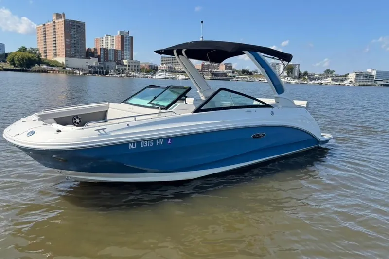 The Image of 2025 Sea Ray SDX 250 Outboard boat on calm water with cityscape background. - 1