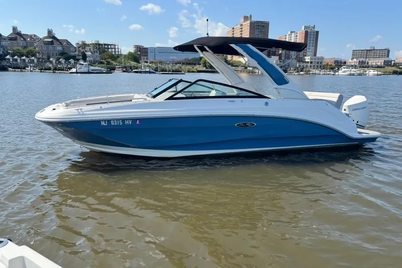Slide: The Image of 2025 Sea Ray SDX 250 Outboard boat on calm water with cityscape background. - 2