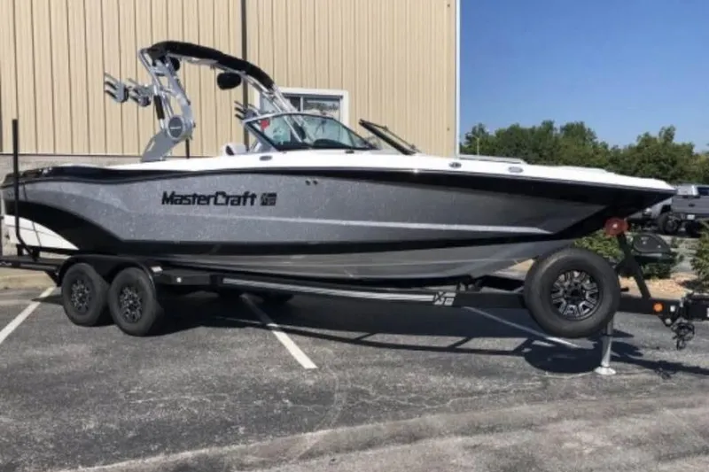 Slide: The Image of 2019 MasterCraft XT25 boat on trailer, parked outdoors. - 2
