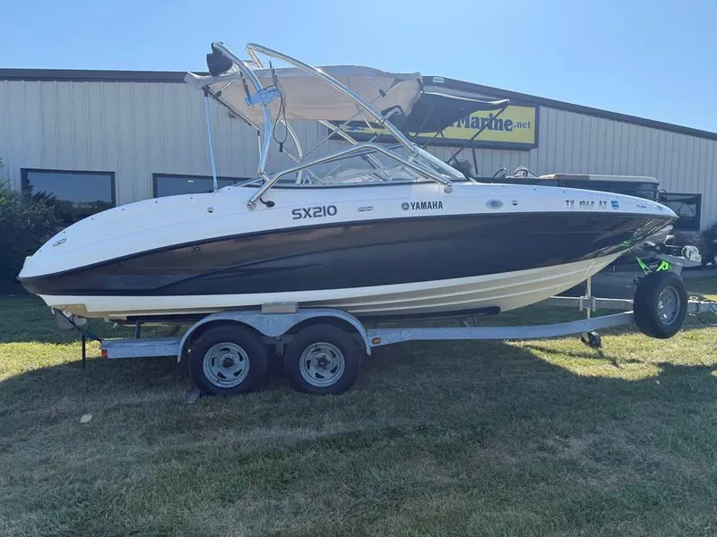The Image of 2007 Yamaha SX210 boat on trailer, parked on grass near a building. - 0