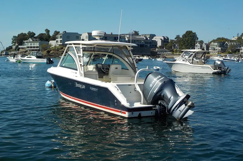The Image of 2013 Pursuit DC 265 Dual Console boat on calm water, surrounded by other boats. - 0