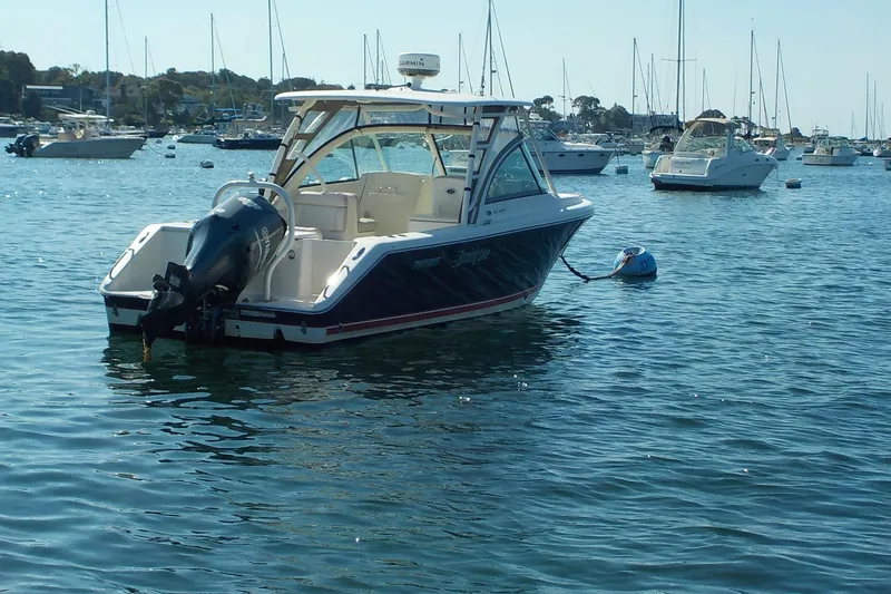 Slide: The Image of 2013 Pursuit DC 265 Dual Console boat anchored in a marina with other vessels. - 1