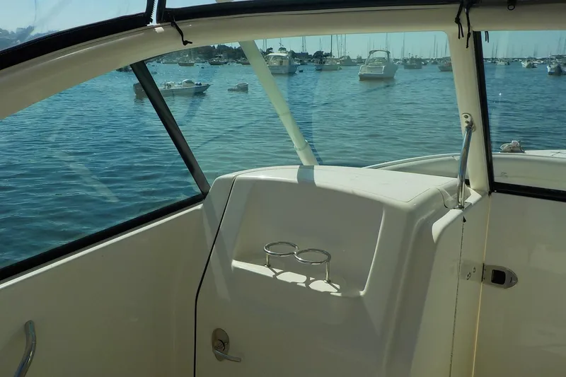 Slide: The Image of 2013 Pursuit DC 265 Dual Console boat interior with ocean view and moored boats. - 12
