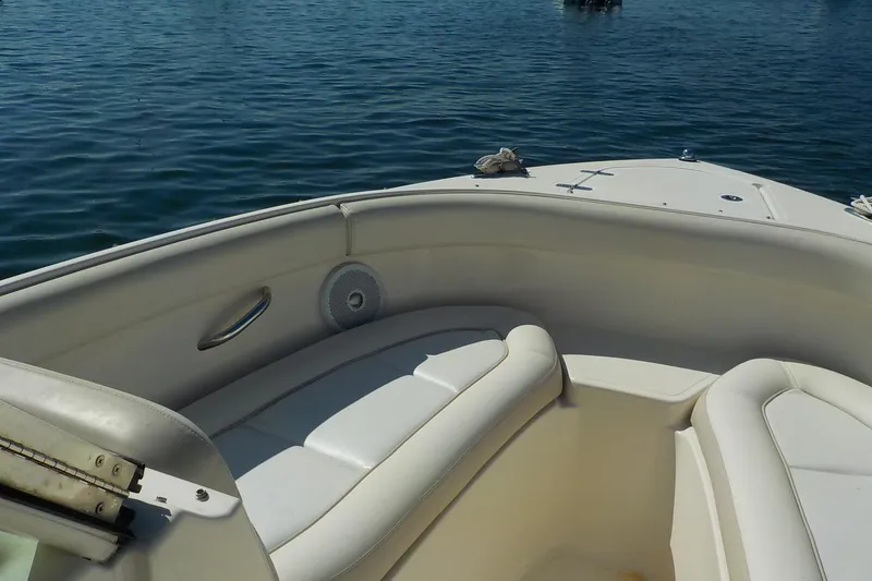 Slide: The Image of 2013 Pursuit DC 265 Dual Console boat interior with white seating on calm water. - 15