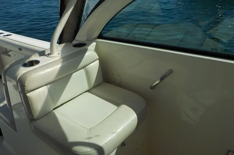 Slide: The Image of 2013 Pursuit DC 265 Dual Console boat interior with white seating and cup holders. - 16