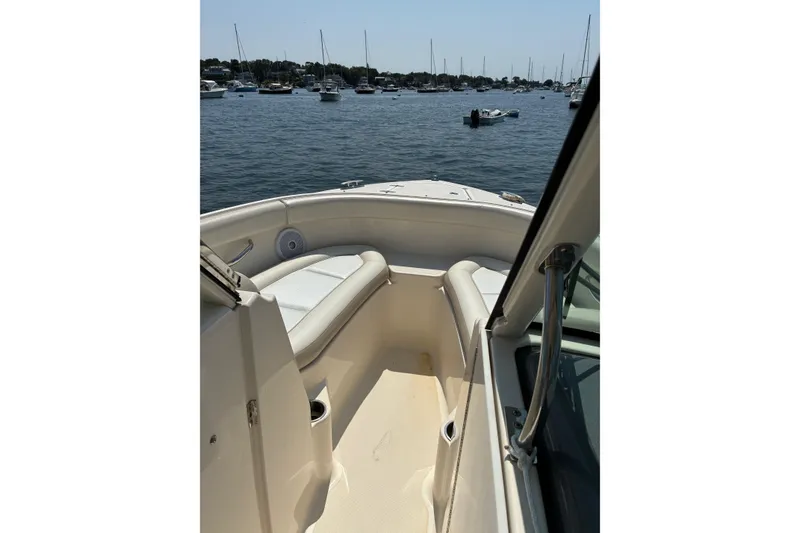 Slide: The Image of 2013 Pursuit DC 265 Dual Console boat interior with seating, on a calm water backdrop. - 20