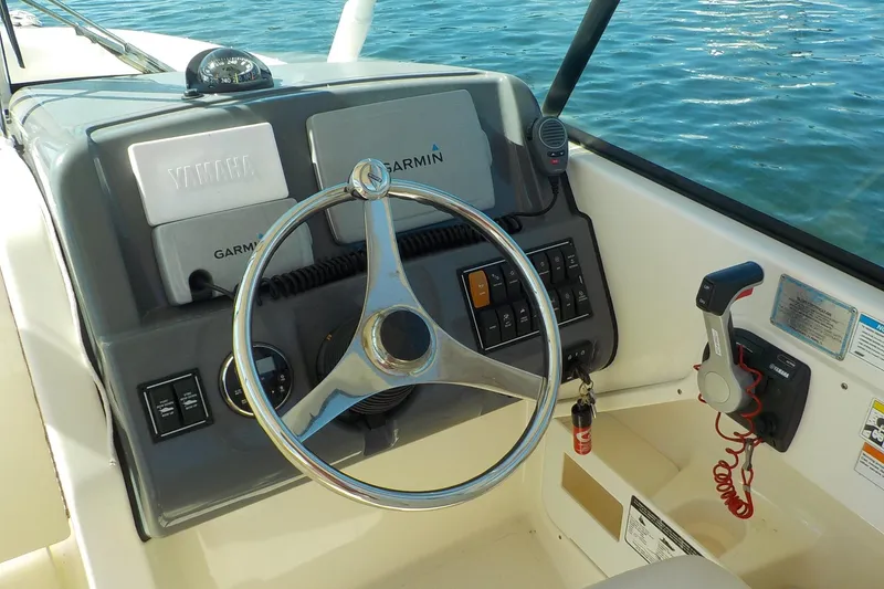 Slide: The Image of 2013 Pursuit DC 265 Dual Console boat dashboard with steering wheel and controls. - 7