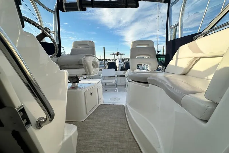 Slide: The Image of 2009 Boston Whaler 285 Conquest interior with seating and helm, under clear blue sky. - 12