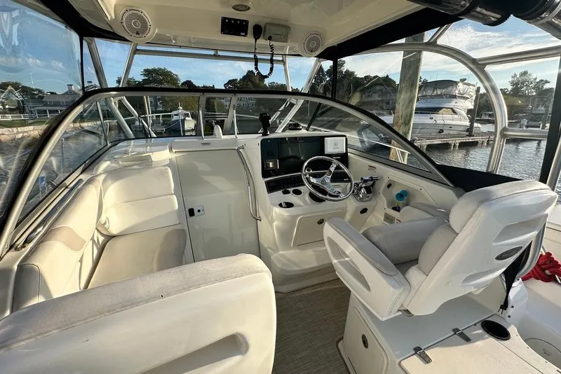 Slide: The Image of 2009 Boston Whaler 285 Conquest boat interior with helm, seating, and marina view. - 2