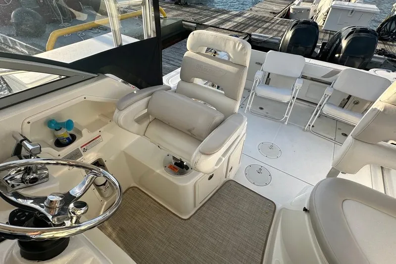 Slide: The Image of 2009 Boston Whaler 285 Conquest boat interior with helm, seating, and dock view. - 5