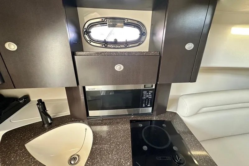 Slide: The Image of 2009 Boston Whaler 285 Conquest interior kitchen with microwave, sink, and stove. - 9