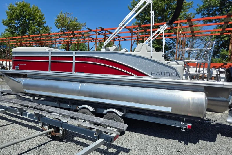 Slide: The Image of 2026 Harris Cruiser 230 pontoon boat on trailer, red and silver design, outdoor setting. - 2
