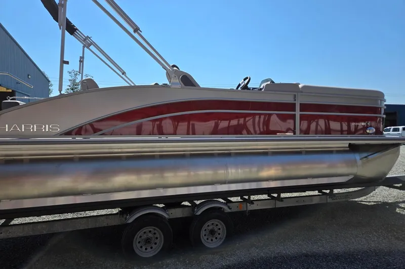 Slide: The Image of 2026 Harris Cruiser 230 pontoon boat on trailer, side view, red and silver design. - 7