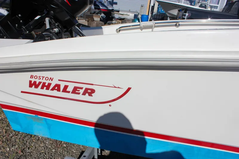 Slide: The Image of 2021 Boston Whaler 130 Super Sport boat with logo and red stripe detail. - 16