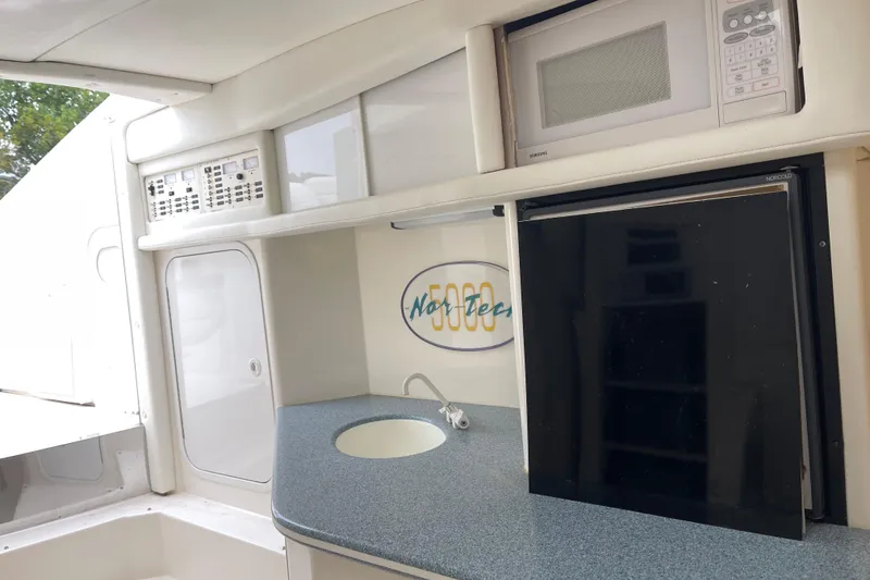 Slide: The Image of Interior of 1998 Nor-Tech 5000V Diesel boat with kitchenette, featuring microwave and mini fridge. - 27