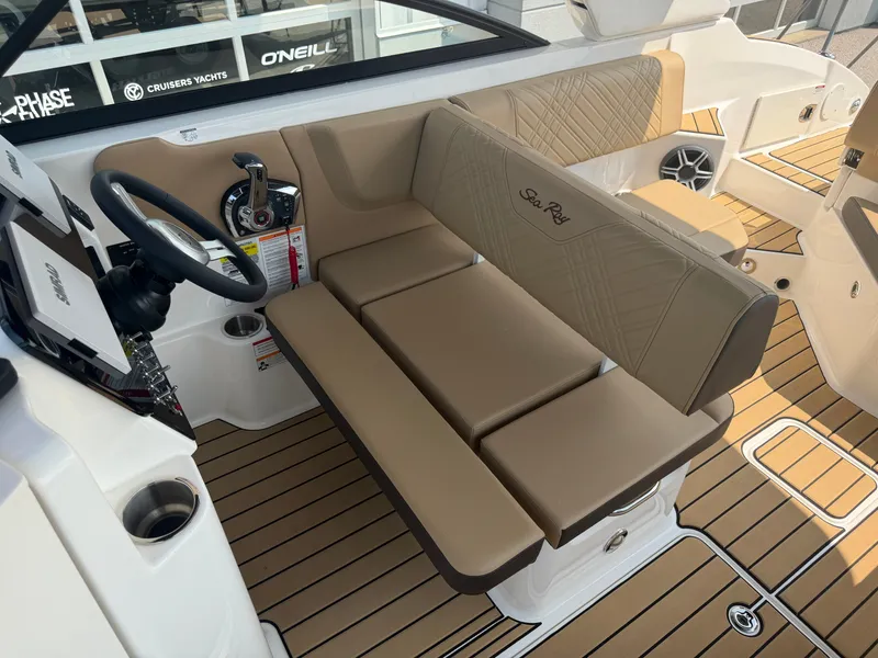 Slide: The Image of The image shows the cockpit of a 2026 Sea Ray SDX 250 Outboard with beige upholstery and wood-pattern flooring. - 26
