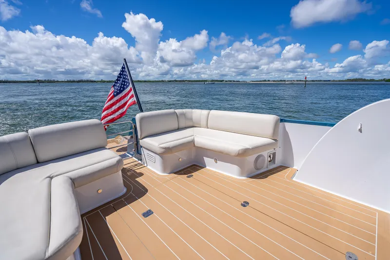Slide: The Image of 2019 Palm Beach Motor Yachts GT50 deck with seating, American flag, and ocean view. - 13