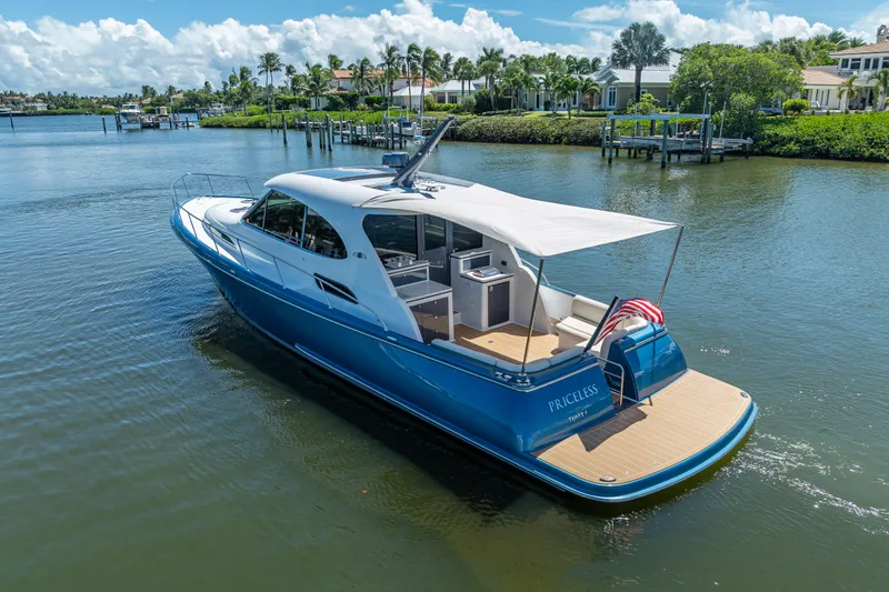 Slide: The Image of 2019 Palm Beach Motor Yachts GT50 cruising on a serene waterway, surrounded by lush greenery. - 7
