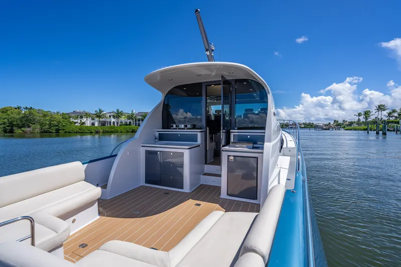 Slide: The Image of 2019 Palm Beach Motor Yachts GT50 on serene water, showcasing luxurious deck and seating. - 9