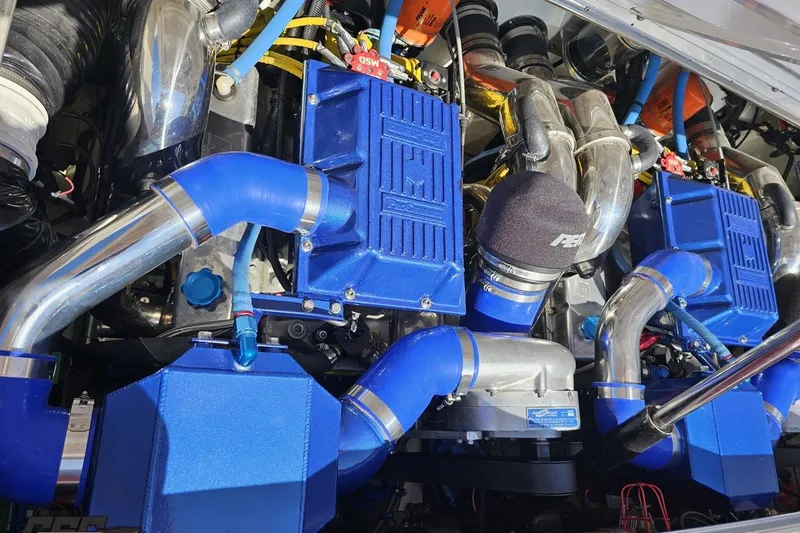 Slide: The Image of Twin blue engines in a 1995 Wellcraft 29 Scarab boat, featuring chrome pipes. - 100