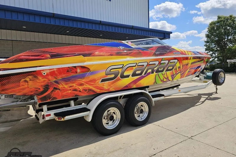 Slide: The Image of 1995 Wellcraft 29 Scarab boat with vibrant flame graphics on a trailer. - 11