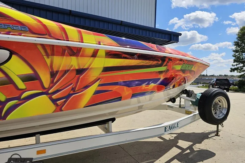 Slide: The Image of 1995 Wellcraft 29 Scarab boat with vibrant, colorful graphics on a trailer. - 12