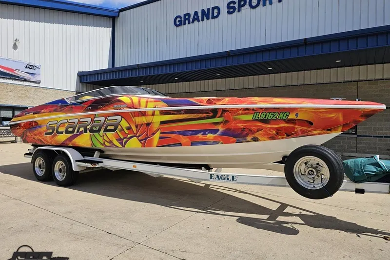 Slide: The Image of 1995 Wellcraft 29 Scarab boat with vibrant flame graphics on a trailer. - 14