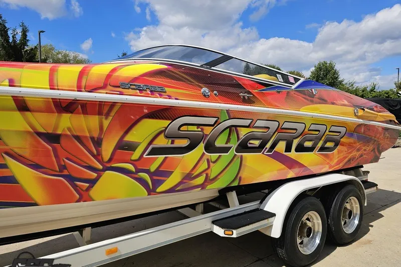 Slide: The Image of Colorful 1995 Wellcraft 29 Scarab speedboat on trailer under blue sky. - 20
