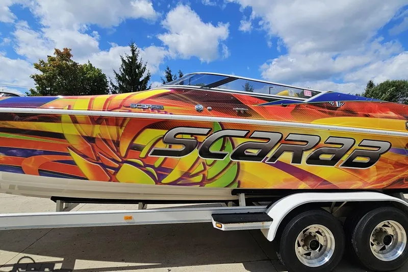 Slide: The Image of Colorful 1995 Wellcraft 29 Scarab boat with vibrant graphics on a trailer. - 24