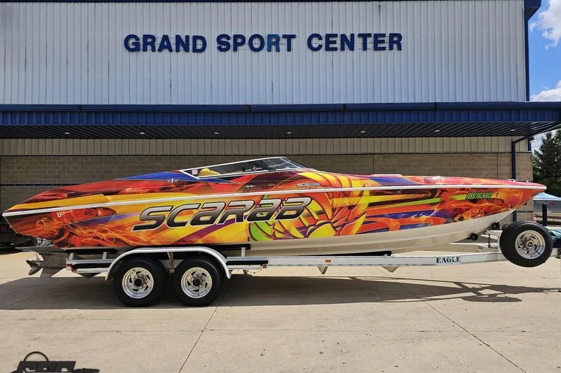 Slide: The Image of 1995 Wellcraft 29 Scarab boat with vibrant graphics at Grand Sport Center. - 3