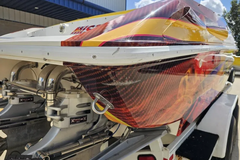 Slide: The Image of 1995 Wellcraft 29 Scarab boat with vibrant custom graphics and powerful engines. - 32